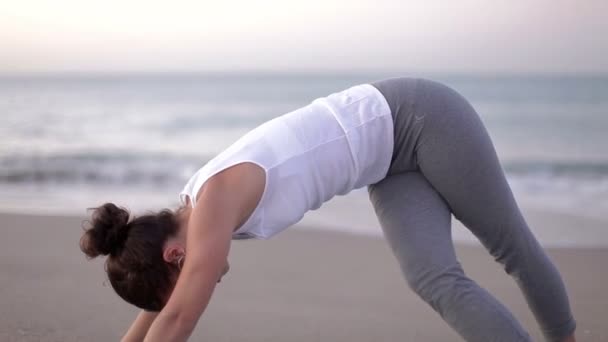 Jovem pratica ioga em uma praia ao nascer do sol — Vídeo de Stock