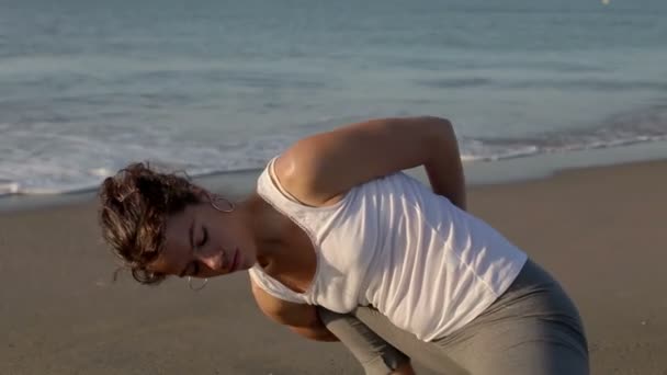 Junge Frau praktiziert Yoga am Strand bei Sonnenaufgang — Stockvideo