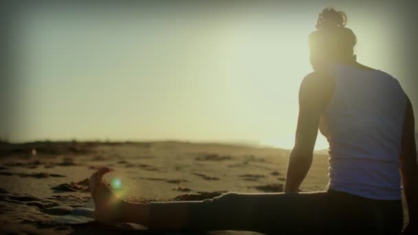 Mujer joven practica yoga en una playa al amanecer — Vídeos de Stock