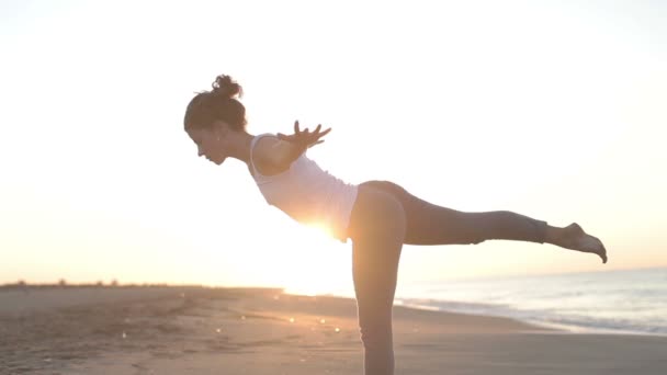 Mujer joven practica yoga en una playa al amanecer — Vídeo de stock