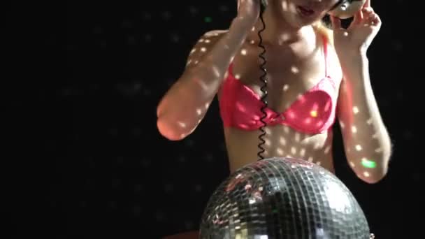 A sexy gogo dancer shot in a studio dancing and posing with a spinning discoball — Stock Video