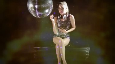 A sexy gogo dancer shot in a studio dancing and posing with a spinning discoball