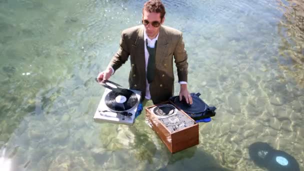 Flippiger DJ im Anzug spielt im Meer — Stockvideo