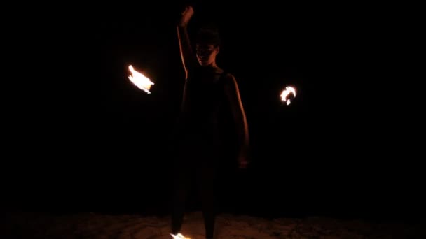 une femme fait un spectacle de feu sur la plage 