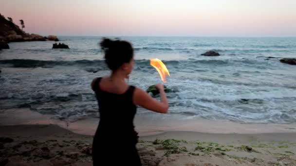 Een vrouw doet een brand performance op het strand — Stockvideo
