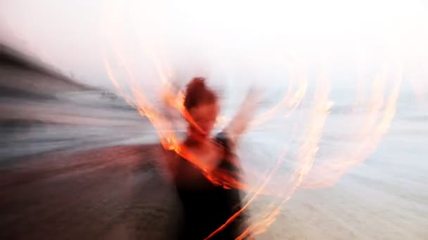 Een vrouw doet een brand performance op het strand — Stockvideo