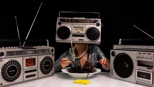 Mujer con ghettoblaster como una cabeza comiendo cinta de cassette — Vídeos de Stock