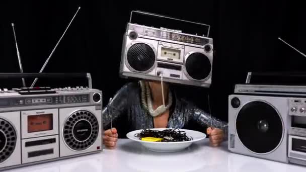 Woman with ghettoblaster as a head eating cassette tape — Stock Video