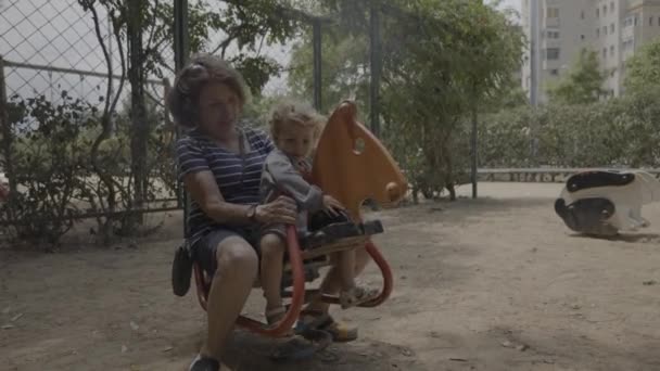 Девочка и бабушка играют в парке на качелях — стоковое видео