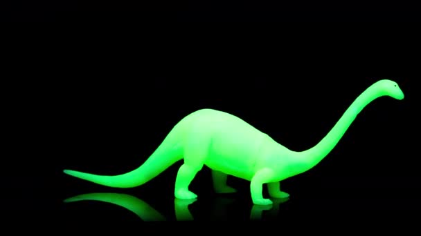 Green toy dinosaur turning agaisnt black — Stock Video