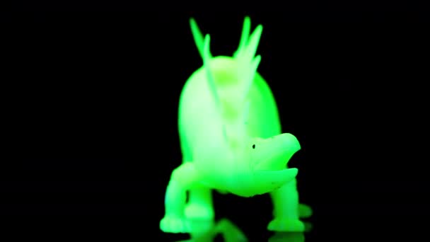 Verde dinosaurio juguete girando agaisnt negro — Vídeos de Stock