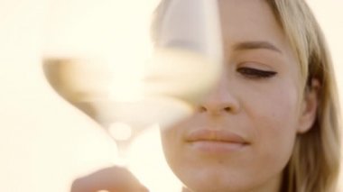 Denize karşı kadehte şarap tutan bir kadın.