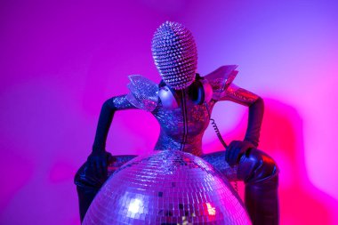 Female dancer with spiky mask against colourful background