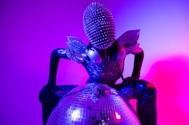Female dancer with spiky mask against colourful background