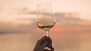 Denize karşı şarap kadehini tutan el.