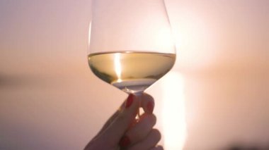 Denize karşı şarap kadehini tutan el.