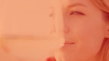 Denize karşı kadehte şarap tutan bir kadın.