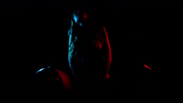 Жінка-танцівниця позує на барвистому фоні — стокове відео