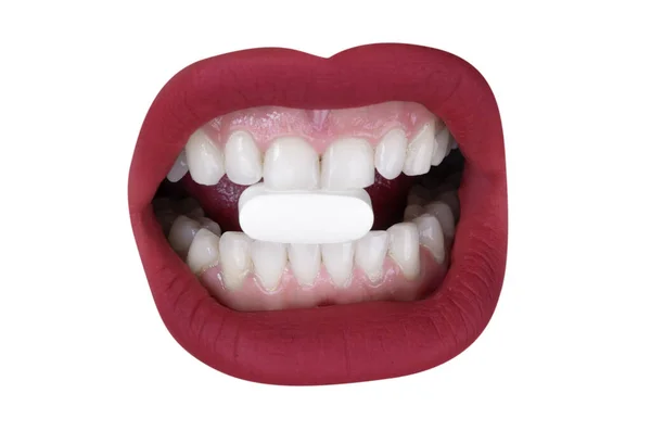 女人美丽而丰满的红唇 牙齿中间夹着白色药丸 — 图库照片