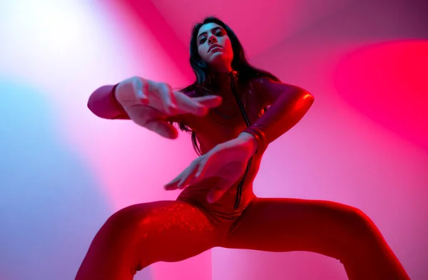 A beautiful female disco dancer in red catsuit and blue and red lighting