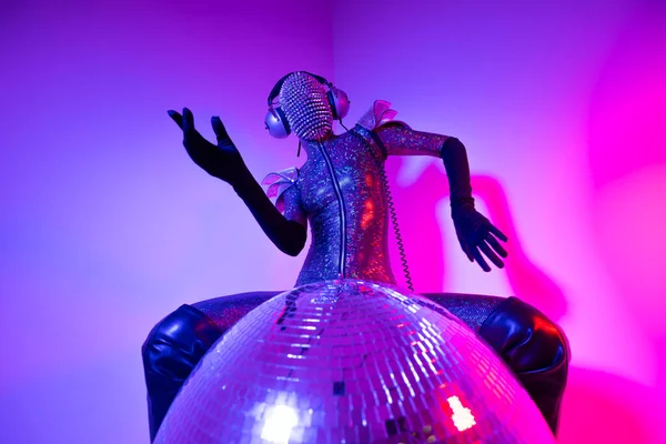 A disco dancer with spiky mask and silver costume against colourful background