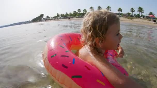 一个小女孩带着一个充气环在海里漂浮和游泳 — 图库视频影像