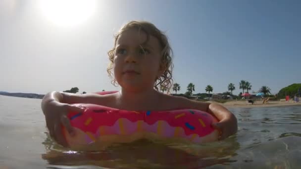一个小女孩带着一个充气环在海里漂浮和游泳 — 图库视频影像