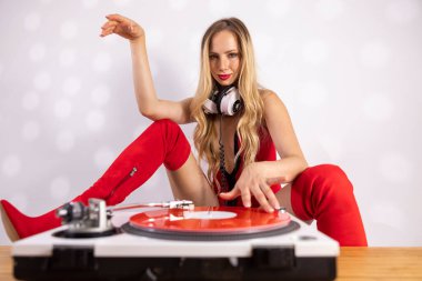 Kırmızı kıyafetli güzel bayan DJ pikaplarla oynuyor.
