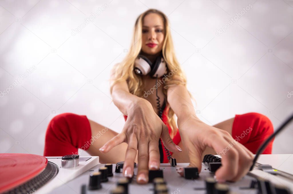 Beautiful female dj in red outfit playing with turntables