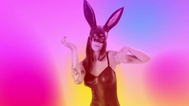 Güzel bir kadın striptizci gotik siyah kostümlü ve tavşan kulaklı pastel renklere karşı.
