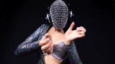 Amazing female dancer with spiked mask against black background