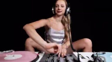 Beautiful female dj playing with turntables in sparkling silver costume and overlayed disco lighting