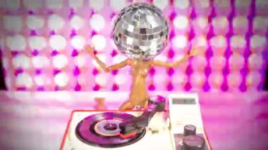 A sparkling DJ doll with a discoball head dances with a record turntable
