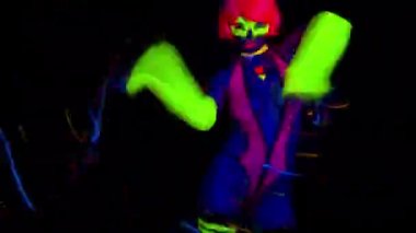 A mix of different cyber raver dancers and Djs filmed in fluorescent clothing under UV black light