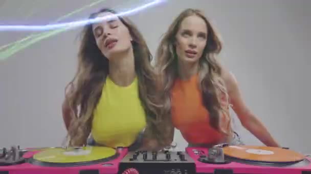 レコードターンテーブルとオーバーレイディスコライトの後ろに踊る同じ双子の女性Dj — ストック動画