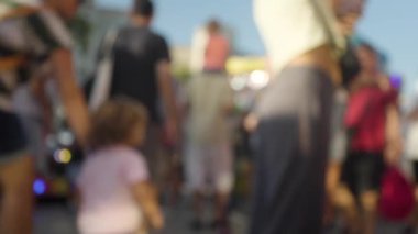 Bir kalabalığın bulanık ve yumuşak bir odak noktasında lunaparkta yürümesi.