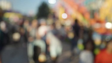 Bir kalabalığın bulanık ve yumuşak bir odak noktasında lunaparkta yürümesi.