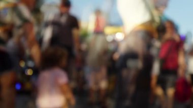 Bir kalabalığın bulanık ve yumuşak bir odak noktasında lunaparkta yürümesi.