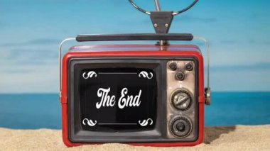 Plajda eski moda sinema başlıkları olan klasik bir televizyon.