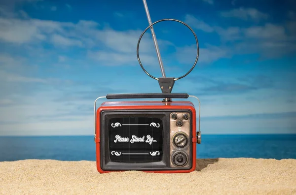 海滩上有一台老式的电视 上面有老式的电影片名 请大家站在旁边 — 图库照片