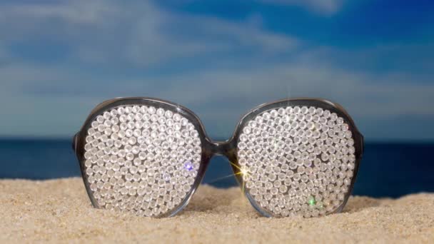Een Paar Kristallen Overdekte Fonkelende Zonnebrillen Het Strand Met Passerende — Stockvideo