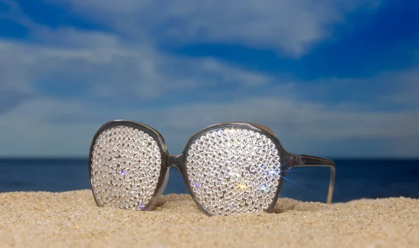 海滩上有一副闪烁着太阳镜的水晶 上面点缀着过往的云彩 — 图库照片