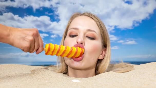 一个漂亮的女人把头埋在海滩上 舔着另一只手捧着的棒棒糖 — 图库视频影像