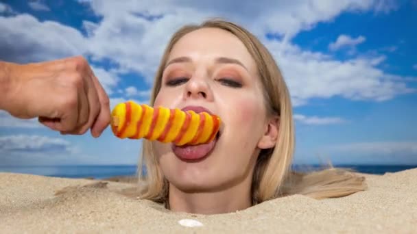 一个漂亮的女人把头埋在海滩上 舔着另一只手捧着的棒棒糖 — 图库视频影像