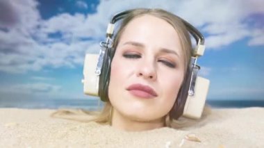 Kafasına kadar plaja gömülü güzel bir kadın kulaklıkla müzik dinliyor.