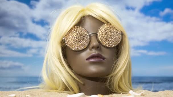 美しいビーチで輝くサングラスで砂の中に閉じ込められたプラスチック製の女性マネキンの頭 — ストック動画