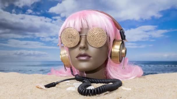 一只塑料女人体模特的脑袋卡在沙滩上 戴着闪闪发光的太阳镜和耳机 — 图库视频影像