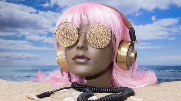 Пластикова Жіноча Голова Манекена Застрягла Піску Ігристими Сонцезахисними Окулярами Навушниками — стокове відео