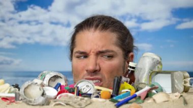 Kafasına kadar çöp ve plastik atıkla kaplı bir plaja gömülü bir adam.