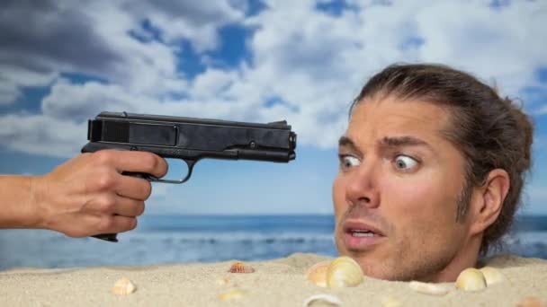 一个男人把头埋在海滩上 用枪指着他的头 — 图库视频影像